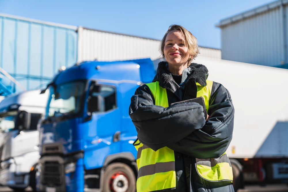 Confident woman working as a professional truck driver near semi trucks